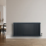 Radiateur traditionnel à 4 colonnes gris anthracite, finition lisse, installé sur un mur clair, avec un sol en bois chaleureux
