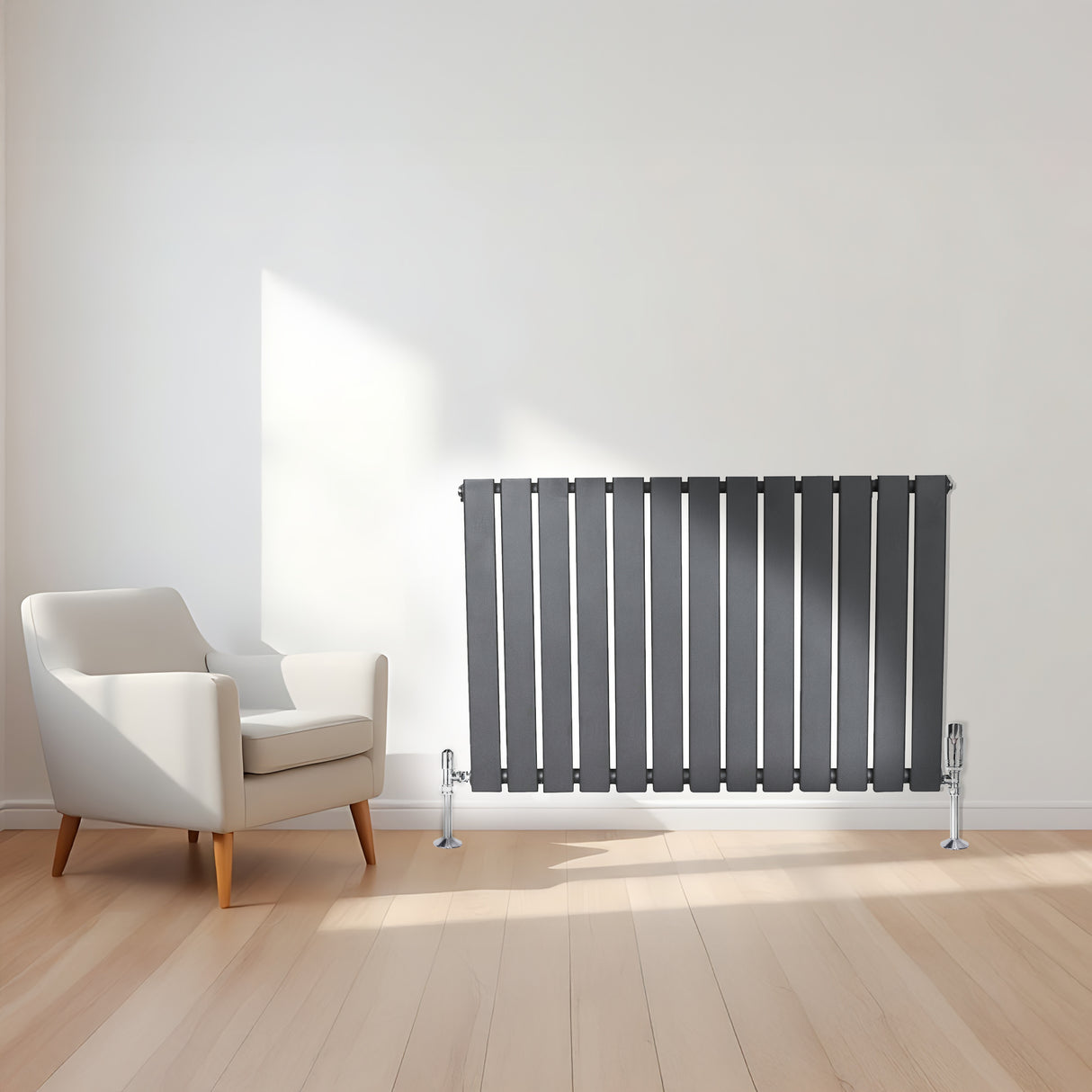 Radiateur plat gris anthracite à un panneau, installé sur un mur, avec des pieds chromés, à côté d'un fauteuil moderne en bois clair