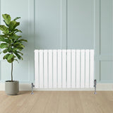 Radiateur plat blanc à un panneau, 600 x 910 mm, installé sous une plante verte dans un intérieur moderne aux murs clairs