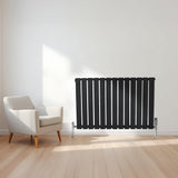 Radiateur plat noir à 1 panneau, design moderne avec lignes verticales, installé sur un mur clair, près d'un fauteuil contemporain