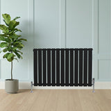 Radiateur plat noir à 1 panneau, 600 x 910 mm, avec finition lisse, installé contre un mur clair, à côté d'une plante verte en pot