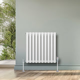 Radiateur à colonnes ovales blanc, 600 x 600 mm, avec finition lisse et pieds chromés, installé dans un intérieur moderne lumineux