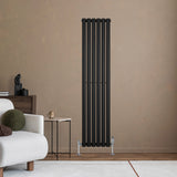 Radiateur à colonnes ovales noir, 1600 x 360 mm, avec une finition lisse et moderne, installé sur un mur beige dans un salon élégant