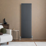Radiateur à colonnes ovales gris anthracite, élégant et moderne, installé dans un intérieur minimaliste avec un mur beige et un mobilier contemporain