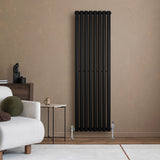 Radiateur à colonnes ovales noir, 1600 x 480 mm, installé sur un mur beige, avec un canapé clair et une table moderne à côté