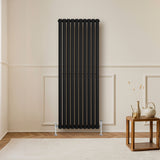 Radiateur à colonnes ovales noir, 1600 x 600 mm, avec finition lisse, installé contre un mur dans un intérieur moderne et minimaliste