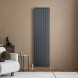 Radiateur à colonnes ovales gris anthracite, 1800 x 480 mm, installé sur un mur beige, avec un mobilier moderne en arrière-plan