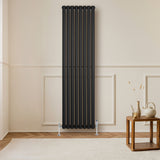 Radiateur à colonnes ovales noir, 1800 x 480 mm, avec finition lisse et moderne, installé contre un mur clair, décor minimaliste