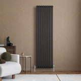 Radiateur à colonnes ovales noir, 1800 x 480 mm, installé contre un mur beige, avec des pieds en métal et un design moderne élégant