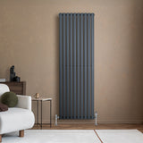 Radiateur à colonnes ovales gris anthracite, 1800 x 600 mm, installé sur un mur beige, avec des pieds en métal et un design moderne