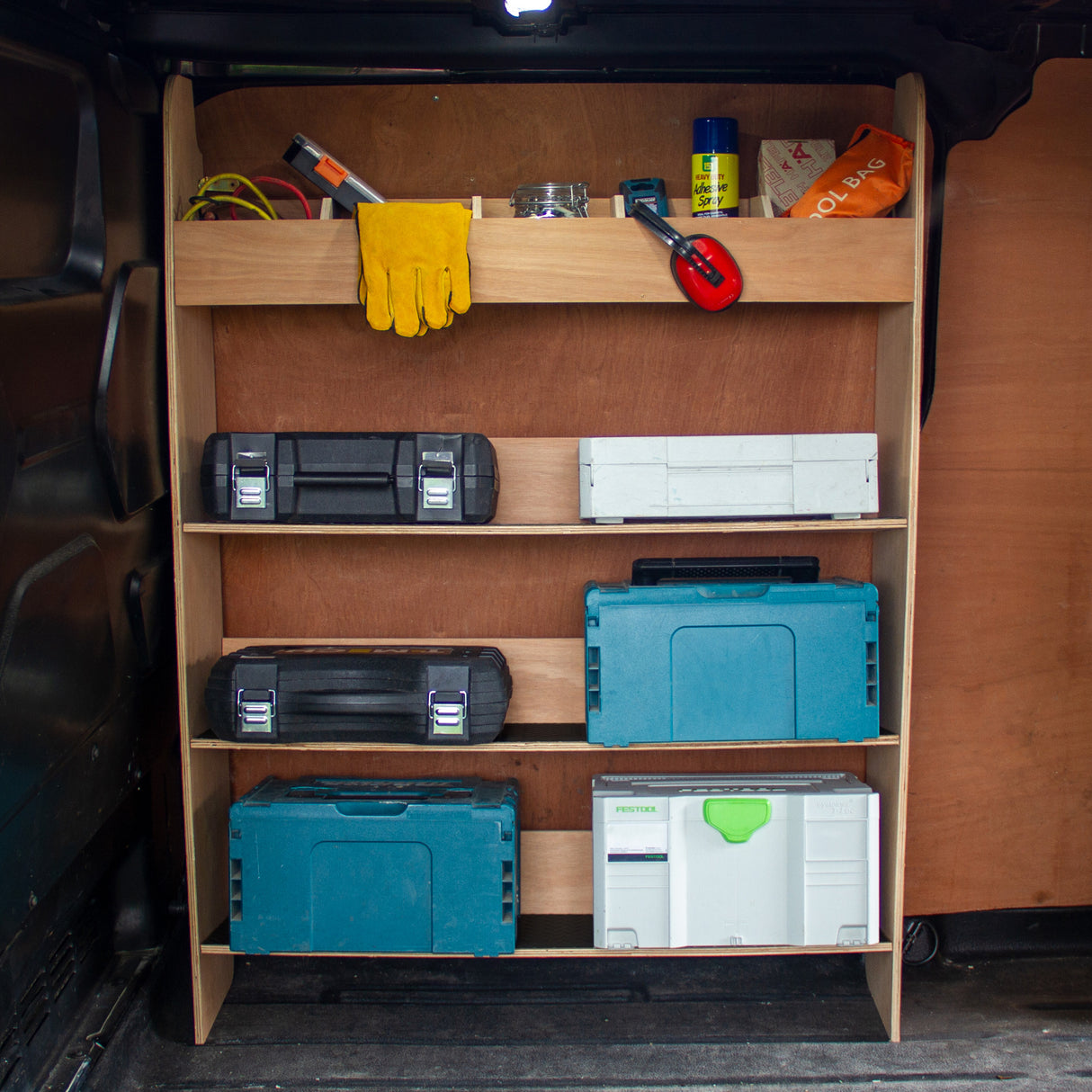 Étagère en contreplaqué avec trois niveaux, outils et boîtes de rangement colorées, idéale pour l'organisation dans un Ford Transit