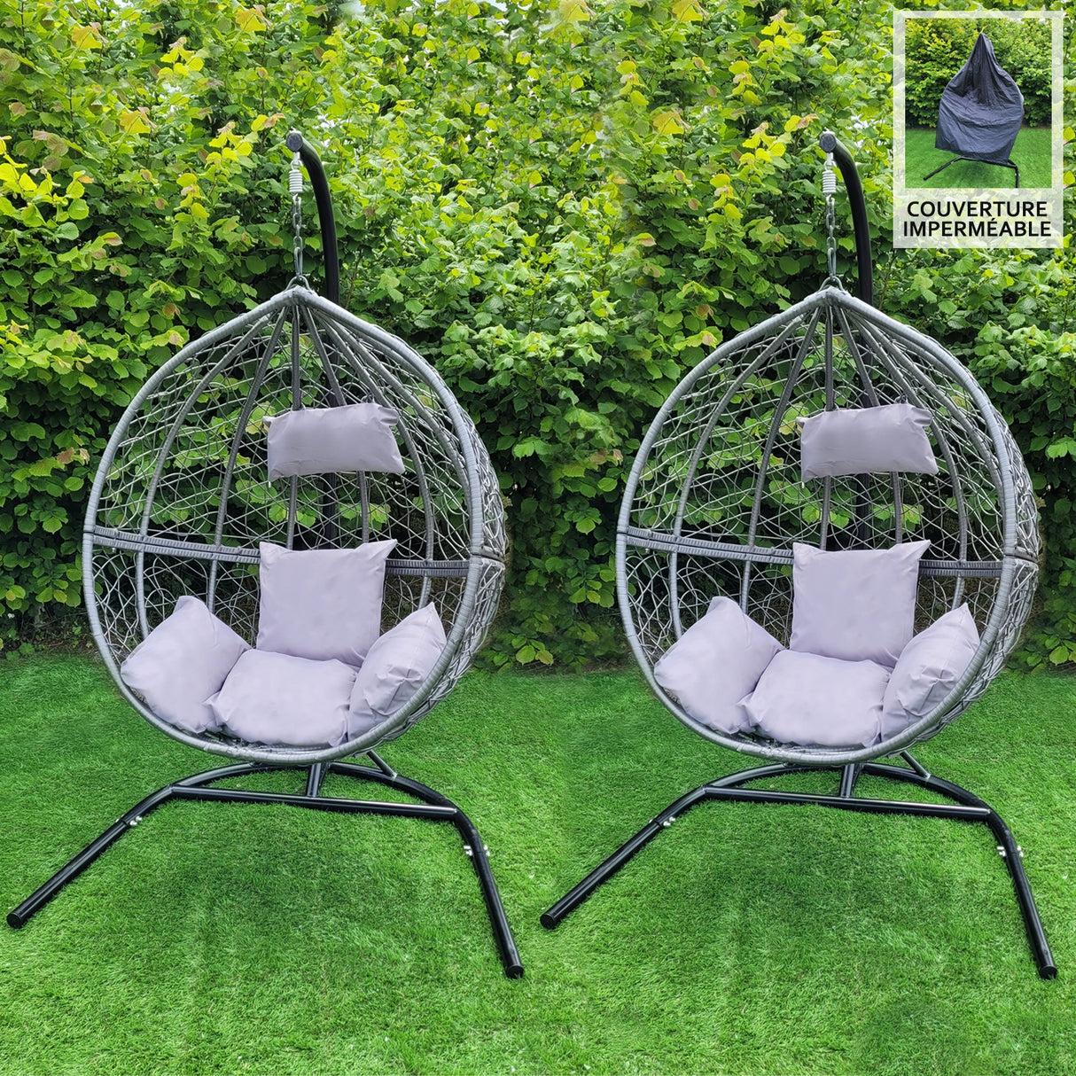 Deux chaises suspendues en rotin gris avec coussins gris, sur un support noir, entourées de verdure luxuriante et d'herbe verte